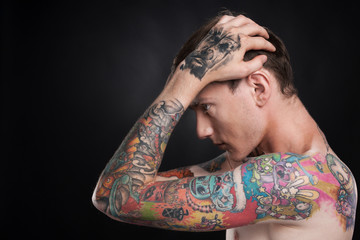 man with tattoo holding head with hands.