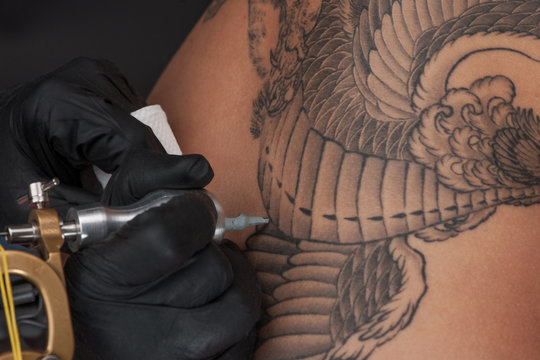 professional tattooist making back tattoo.