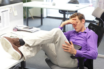 Young businessman  snoozing over  his   tablet in office