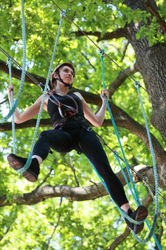 attractive woman climbing in adventure rope park