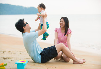 asian family enjoying quality time on the beach with father, mot
