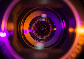 Video camera lens closeup lit by orange and purple neon light - obrazy, fototapety, plakaty