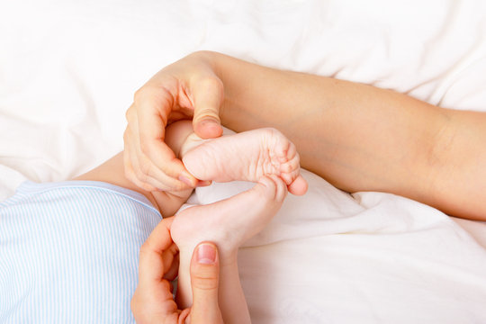 Woman gently holding newborn's feet together