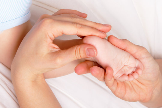 Woman gently pressing newborn's foot