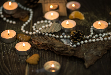 Tea candles and pearl beads on a rustic surface