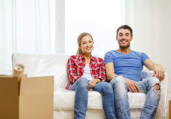 Obraz premium smiling couple relaxing on sofa in new home