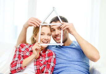 smiling couple with house from measuring tape