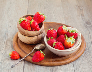Strawberries in plates on wooden table