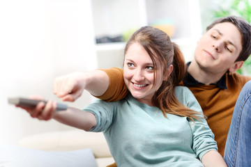 beautiful couple bickering to change tv channel on remote contro