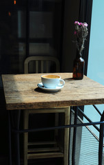 Coffee cup and flower vase on table