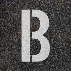 Stencil alphabet letters paint on asphalt road 