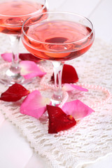 Composition with pink sparkle wine in glasses and rose petals