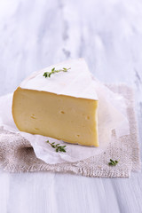 Tasty Camembert cheese with thyme, on wooden table