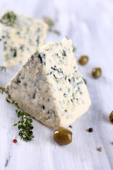Tasty blue cheese with thyme and olives on wooden table