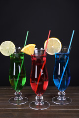 Glasses of cocktails on table on black background