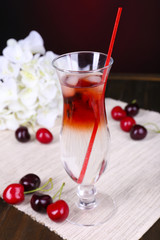 Glass of cocktail on table on dark red background