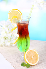 Glass of cocktail on table on light blue background