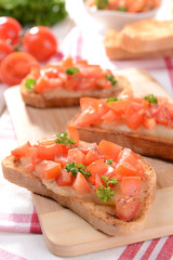 Delicious bruschetta with tomatoes on cutting board close-up