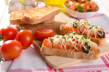 Delicious bruschetta with tomatoes on cutting board close-up