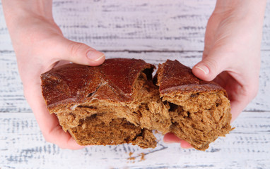 Hands breaking bread on wooden background