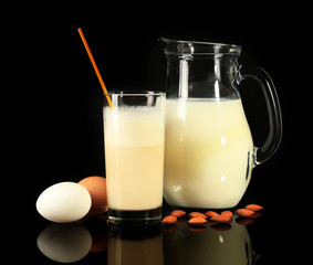 Eggnog with milk and eggs on black background