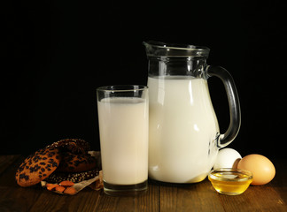 Eggnog with milk and eggs on table and black background