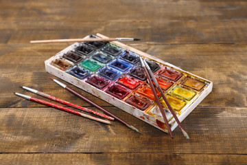 Colourful watercolors and brushes on wooden background