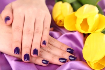Fototapeta premium Beautiful woman hands with flowers on fabric background