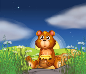 Fototapeta premium A bear at the hilltop holding a pot of honey