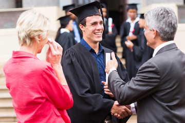 male graduate handshaking with his grandfather