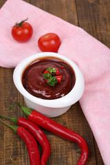 Tomato sauce in bowl on wooden table close-up