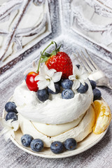 Meringue decorated with blueberries, strawberries and orange