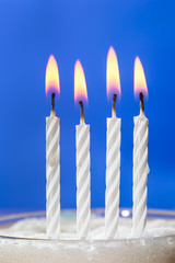 Burning white candles over blue background