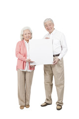 .Senior couple holding white board.