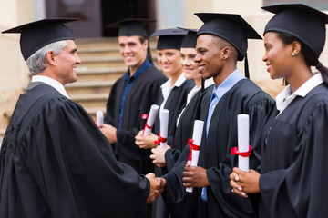 professor handshaking with graduates