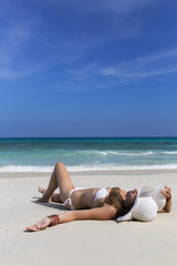 Fototapeta na wymiar Summer vacation woman laying on beach holding beach hat.