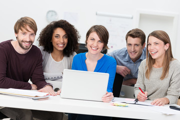 motivierte gruppe mit laptop am schreibtisch
