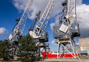 Fototapeta na wymiar Horizontal color image of 3 old cranes in docks.