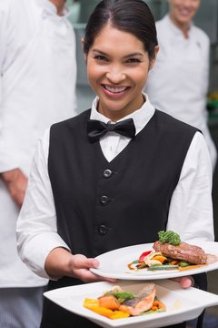 Happy Waitress Holding Steak Dinner And Salmon Dinner