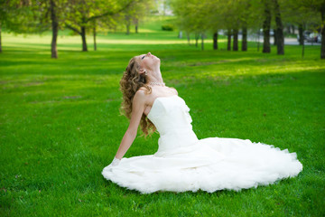 Naklejka premium Beautiful bride in a white dress on green grass in summer