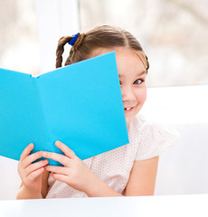 Little girl is reading a book