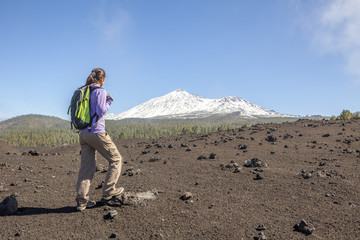 Fototapeta premium young woman on top of a mountain enjoying the view of volcano te