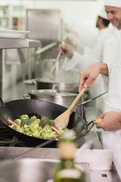 Chef frying broccoli in a wok