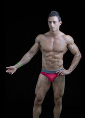 Fototapeta na wymiar Muscular young bodybuilder in relaxed pose, one arm up.