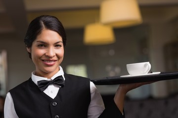 Pretty waitress holding a tray with a cup
