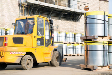 Forklift stacker transporting steel roll with pallet outdoors