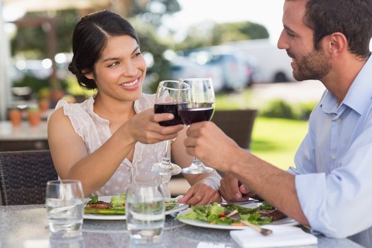 Happy couple on a date toasting with red wine - Powered by Adobe