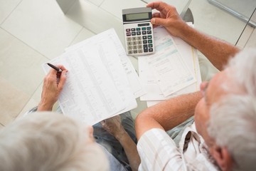 Senior couple using the calculator to pay bills