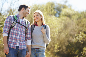 Obraz premium Couple Hiking In Countryside Wearing Backpacks