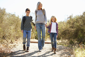 Mother And Children Hiking In Countryside Wearing Backpacks